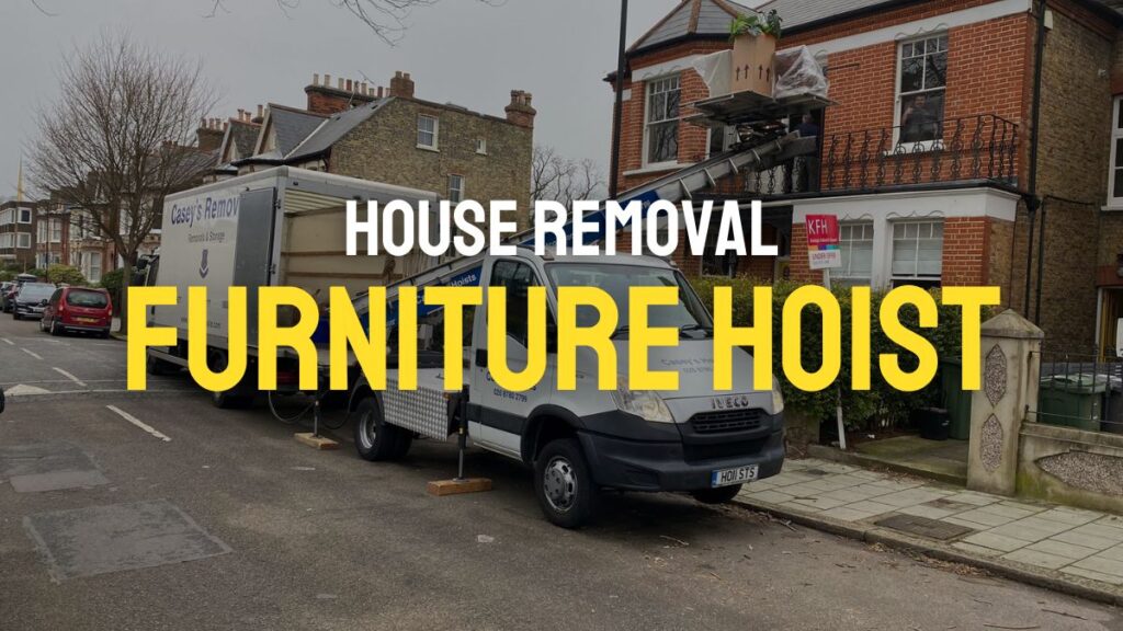 House Removal Truck with Casey's Removals printed on side parked outside a house with a hoist moving items from top window.